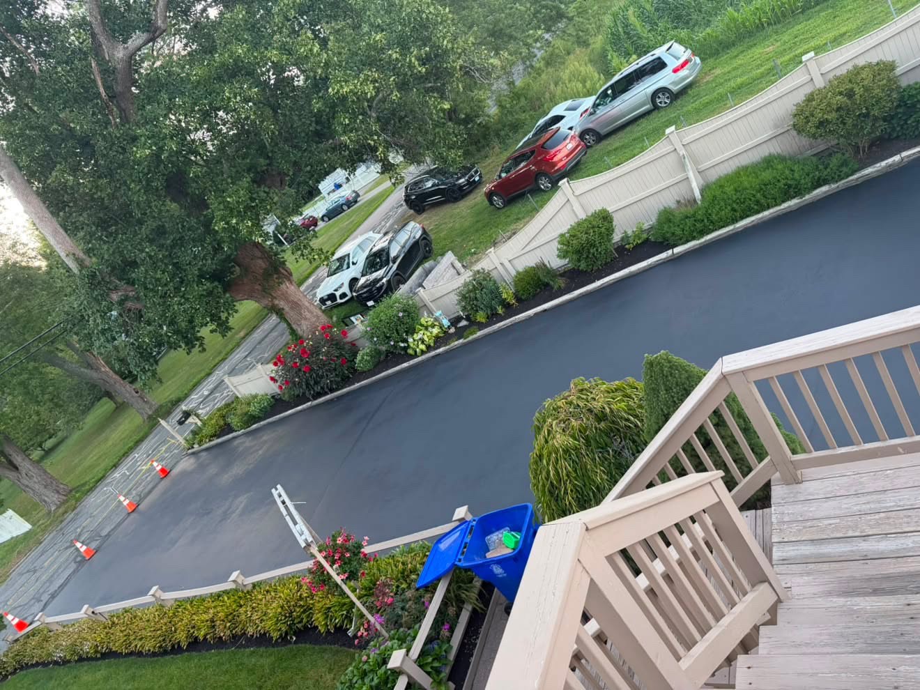 Long sealcoated driveway with deep black finish beside a landscaped yard