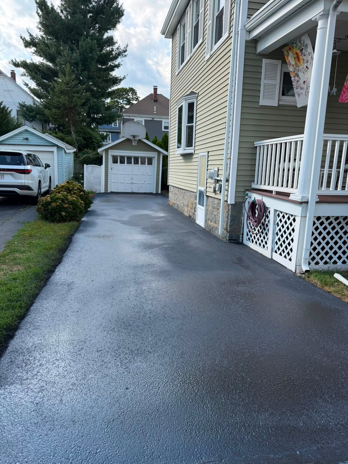 Freshly sealcoated wide residential driveway leading to a two-car garage
